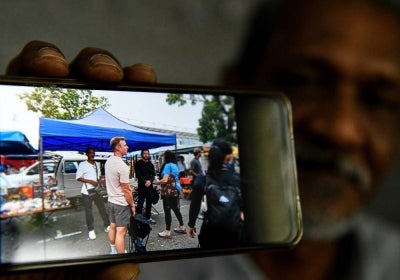 Rope Walk collectibles trader Sheikh Mokhtar Sheikh Ali, 60, shows a photograph of himself with Hollywood star Mark Wahlberg, taken while he was working as an extra during the filming of Netflix's The Big Fix at Rope Walk, Lorong Kulit, today. Photo by Bernama