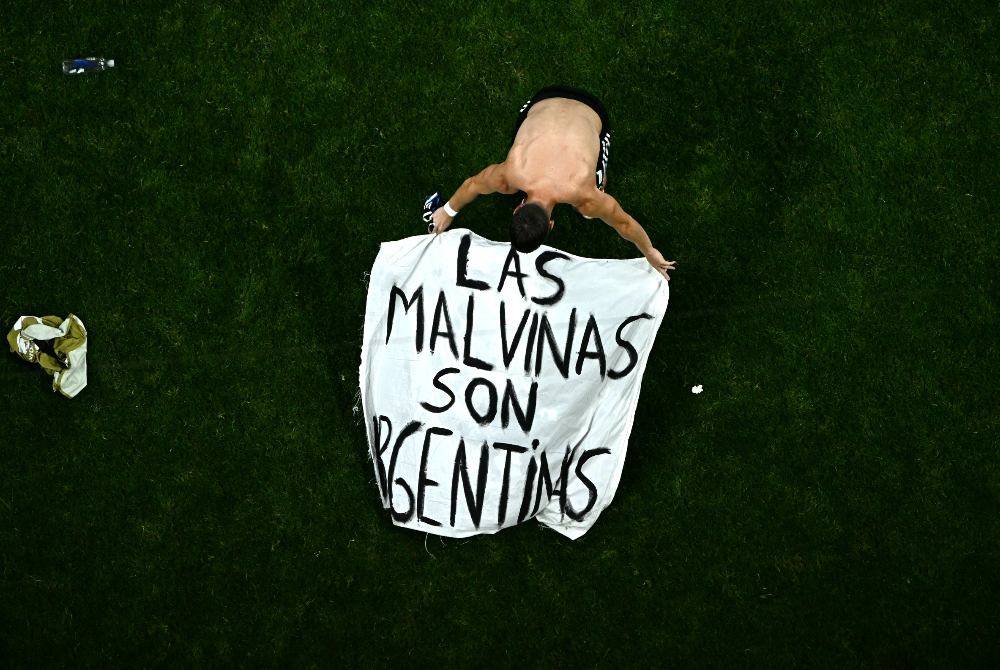 Argentina's midfielder #11 Giovani Lo Celso adjusts a banner reading