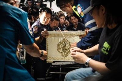 Responders transport a coffin bearing the remains of a victim killed in a bar fire, at the Police General Hospital in Bangkok on July 14. Photo by Chanakarn Laosarakham/AFP