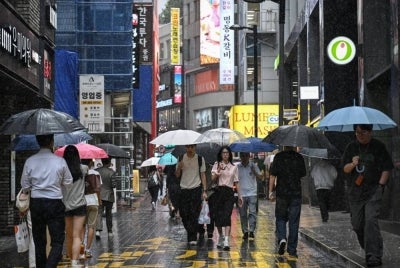 People use umbrellas to shelter from the rain in Seoul on July 9, 2026. - (Photo by JADE GAO / AFP)