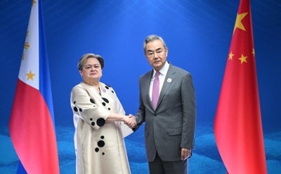 Philippine Secretary of Foreign Affairs Theresa Lazaro (L) shakes hands with China's Foreign Minister Wang Yi (Photo by Ted ALJIBE / POOL / AFP)