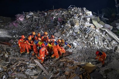  Hundreds of rescue workers have been deployed to the scene, where footage from state media showed a huge pile of rocks and earth had collapsed into a residential and commercial street. (Photo by CNS / AFP) /