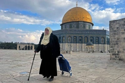 A Palestinian woman walks past the Dome of the Rock at the compound of the Al-Aqsa mosque in the Old City of Jerusalem. Photo by Ahmad Gharabli/AFP