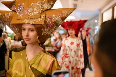Models wearing Tengkuluk Tanduak or Tikuluak Tanduak traditional headgear in outfits from Royal Sembilan.