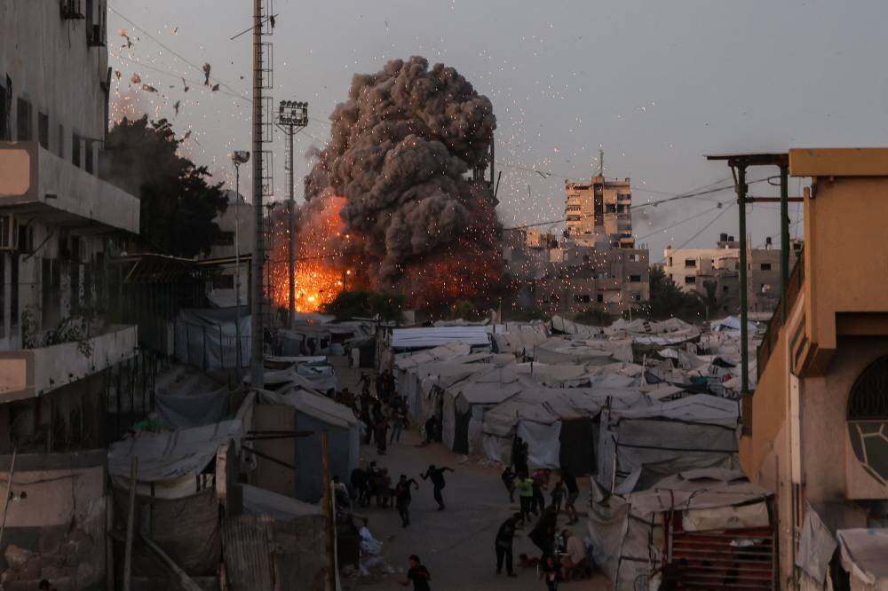 Palestinians run for cover as smoke and fire rise during an Israeli strike on the the Al-Muttaqin Mosque in Gaza City on July 28, 2026. - (Photo by OMAR AL-QATTAA / AFP)