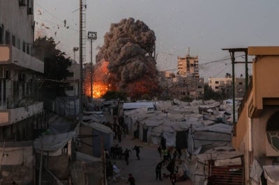 Palestinians run for cover as smoke and fire rise during an Israeli strike on the the Al-Muttaqin Mosque in Gaza City on July 28, 2026. - (Photo by OMAR AL-QATTAA / AFP)