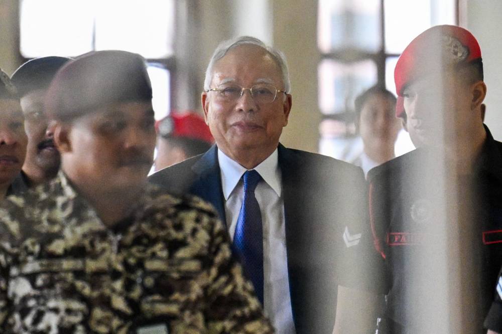 Former Malaysian prime minister Najib Razak (C) is escorted by prison officers during an appeal hearing at the Kuala Lumpur High Court on June 5, 2024. (Photo by Mohd RASFAN / AFP)