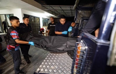Police officers carrying the body of a local man following the death of a resident at a care home in Tanjung Rambutan on 4 August. BERNAMA photo
