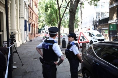 Police officers stand beside cordon tape at Endell road in covent garden, central London on August 5, 2026. A woman was arrested after four men were stabbed in Covent Garden, a busy area of central London popular with tourists, the Metropolitan Police said on August 5. The victims were four men aged 34, 39, 42 and 52, police said, adding that it was "believed to be a mental health related incident" based on the early stages of the probe. (Photo by Henry Nicholls / AFP)