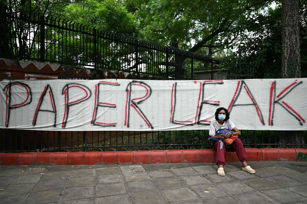 A Cockroach Janta Party (CJP) supporter sits at Jantar Mantar in New Delhi on July 23, 2026 during the ongoing protest to demand the resignation of India's Education Minister Dharmendra Pradhan over alleged NEET exam irregularities. Two weeks after youth-led protests forced India's education minister to resign, Prime Minister Narendra Modi's government is grappling with the fallout from one of its toughest political challenges in years. Led by the online Cockroach Janta Party (CJP), the demonstrations spread from New Delhi to other cities, broadening from anger over exam irregularities into a wider movement over unemployment, opportunities for young people and what critics describe as Modi's increasingly authoritarian rule. (Photo by Sajjad HUSSAIN / AFP)