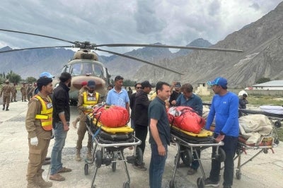 [Graphic content] Rescue personnel carry the bodies of deceased climbers upon arrival at a military base in Skardu in Pakistan's Gilgit-Baltistan on August 6, 2026. The avalanche struck on July 30, cutting off contact with the 10-member international expedition led by 43-year-old British-Nepali climber Purja on Broad Peak, one of the world's highest mountains. His company confirmed there were no survivors. (Photo by Manzoor BALTI / AFP)