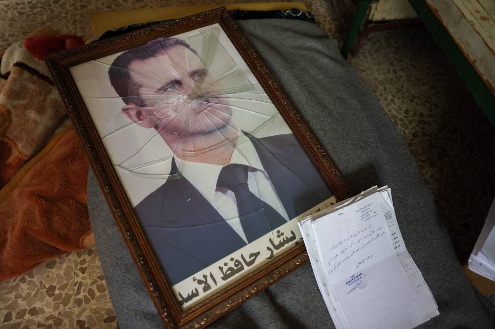 A portrait of Syrian President Bashar al-Assad is pictured with its frame broken, at a Political Security Branch facility on the outskirts of Hama following the capture of the area by anti-government forces on December 7, 2024. A Syrian court sentenced former ruler Bashar al-Assad in absentia to death on August 11, 2026, accusing him of "war crimes" and "crimes against humanity" after the outbreak of the country's civil war in 2011. The ruling is the first under the transitional authorities who this year began trying figures from the former government, both in person and in absentia. AFP photo