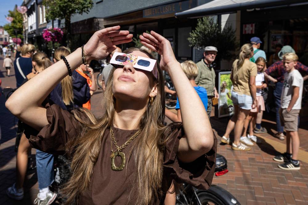 A woman wears eclipse glasses in Almelo, eastern Netherlands on Aug 11, 2026 on the eve of a partial solar eclipse. The scramble for protective glasses has reached fever pitch across Europe ahead of Aug 12, 2026 rare total solar eclipse, as pharmacies, opticians and other shops struggled to keep them in stock. - (Photo by Vincent Jannink / ANP / AFP)