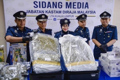 Kuala Lumpur International Airport Customs Director Aspalila Ag Tuah (centre) displays seized cannabis buds during a press conference regarding a cigarette and cannabis smuggling syndicate at the Cargo Customs Complex. - BERNAMA photo