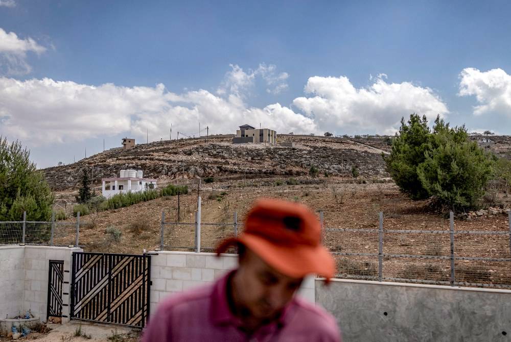 A Palestinian man stands in the yard of a house in the occupied West Bank village of Qusra on Aug 18, 2026, where Israeli settlers are besieging three Palestinian homes. - (Photo by ILIA YEFIMOVICH / AFP)