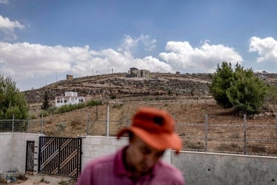 A Palestinian man stands in the yard of a house in the occupied West Bank village of Qusra on Aug 18, 2026, where Israeli settlers are besieging three Palestinian homes. - (Photo by ILIA YEFIMOVICH / AFP)