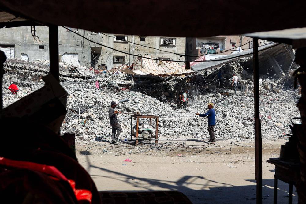 Salvage workers scrap steel rods from the rubble of a building that was destroyed during Israel's war against Hamas in Gaza, to use the recycled remains in the future, in Gaza City on Aug 16, 2026. - (Photo by OMAR AL-QATTAA / AFP)
