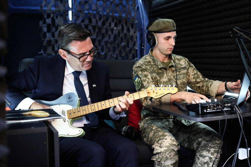 Britain's Prime Minister Andy Burnham (L) plays the guitar in the mobile recording studio of the military and artistic unit who perform on the front lines, in hospitals, and at rehabilitation centres, Cultural Forces Frontline, in Kyiv. Photo by AFP