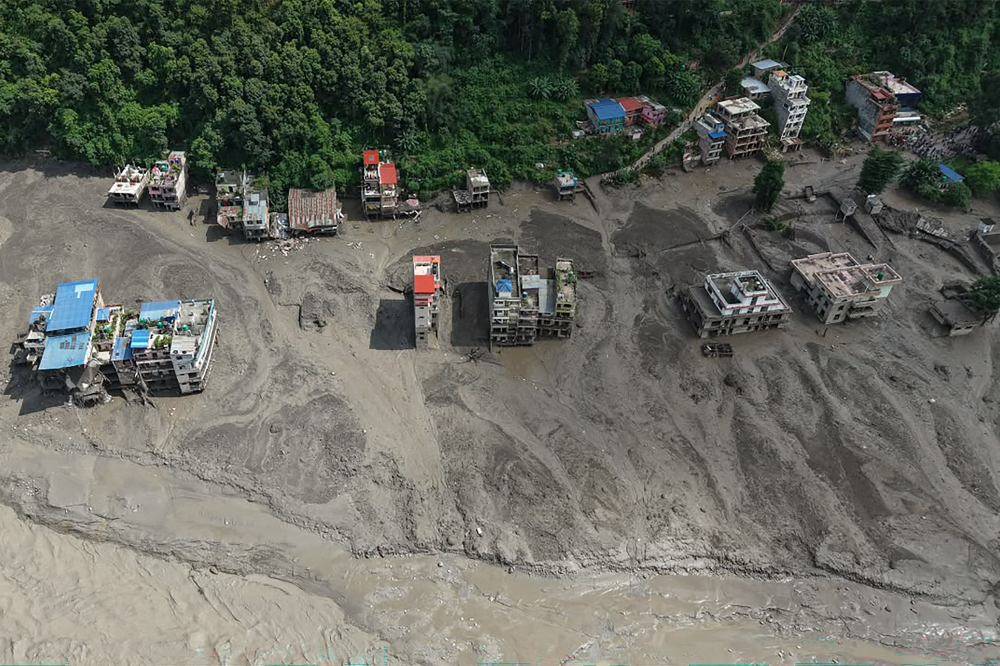 Houses lie partially submerged in muddy water along a riverside after flash floods at Trishuli Bazar in Nepal's Nuwakot district. Photo by AFP