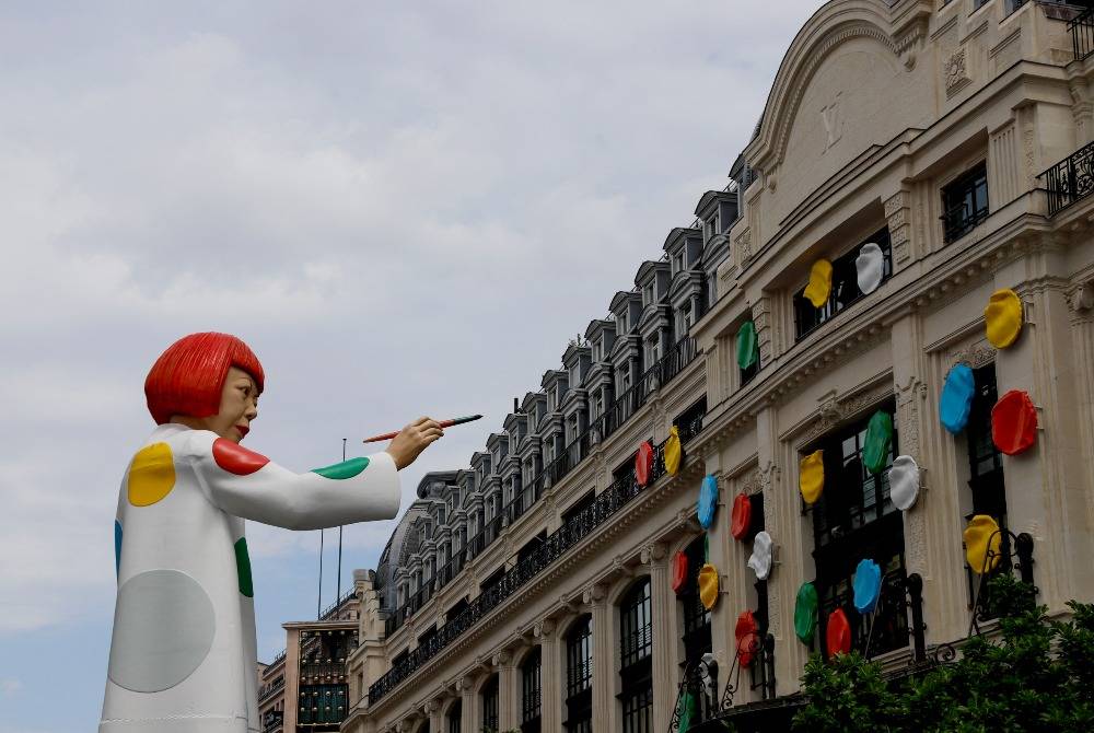 This photograph taken on June 20, 2023 shows a statue depicting the Japanese contemporary artist Yayoi Kusama painting the facade of the headquaters of French luxury brand Louis Vuitton in Paris. - (Photo by AFP)