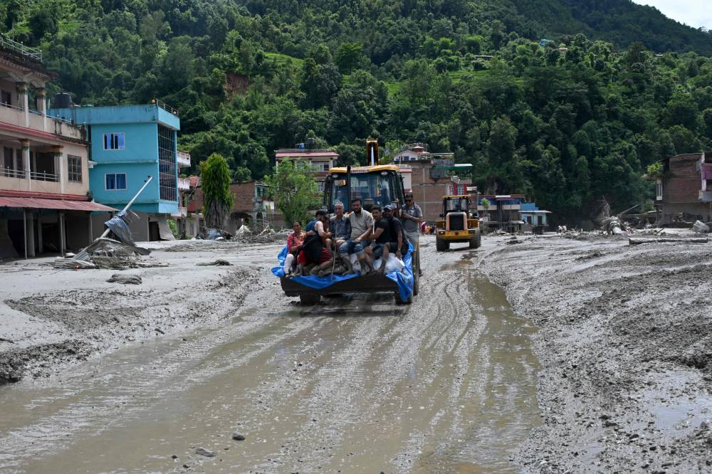 Rescue personnel transport stranded residents using a bulldozer after flash floods in the Devighat area in Nepal's Nuwakot district. Photo by AFP