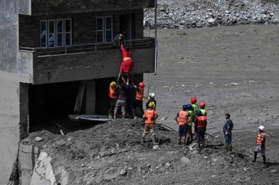 Police personnel rescue stranded residents from a house buried in sludge after flash floods at Trishuli in Nepal's Nuwakot district on Aug 27, 2026. - (Photo by ARUN SANKAR / AFP)