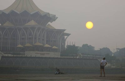 A gloomy-looking sun obscured by haze is seen near the Sarawak State Legislative Assembly building today. - Photo by Bernama