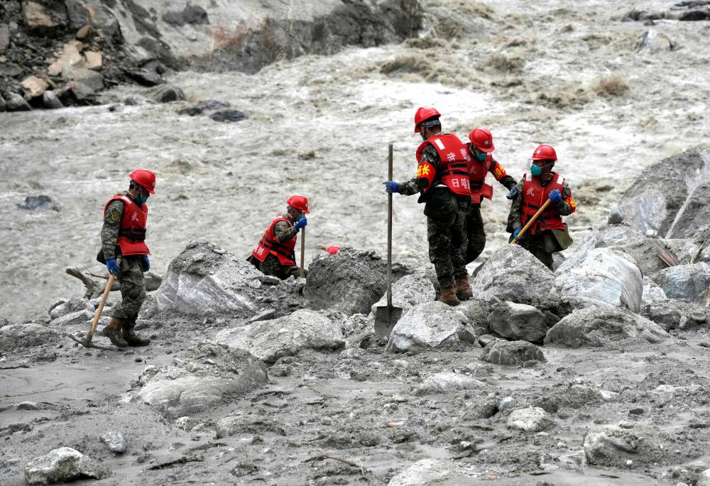 Rescue personnel search through the debris left by a mudslide in the hardest-hit area around the destroyed Gyirong Port in Gyirong County, in China western Tibet region. Photo by CNS/AFP