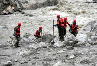 Rescue personnel search through the debris left by a mudslide in the hardest-hit area around the destroyed Gyirong Port in Gyirong County, in China western Tibet region. Photo by CNS/AFP