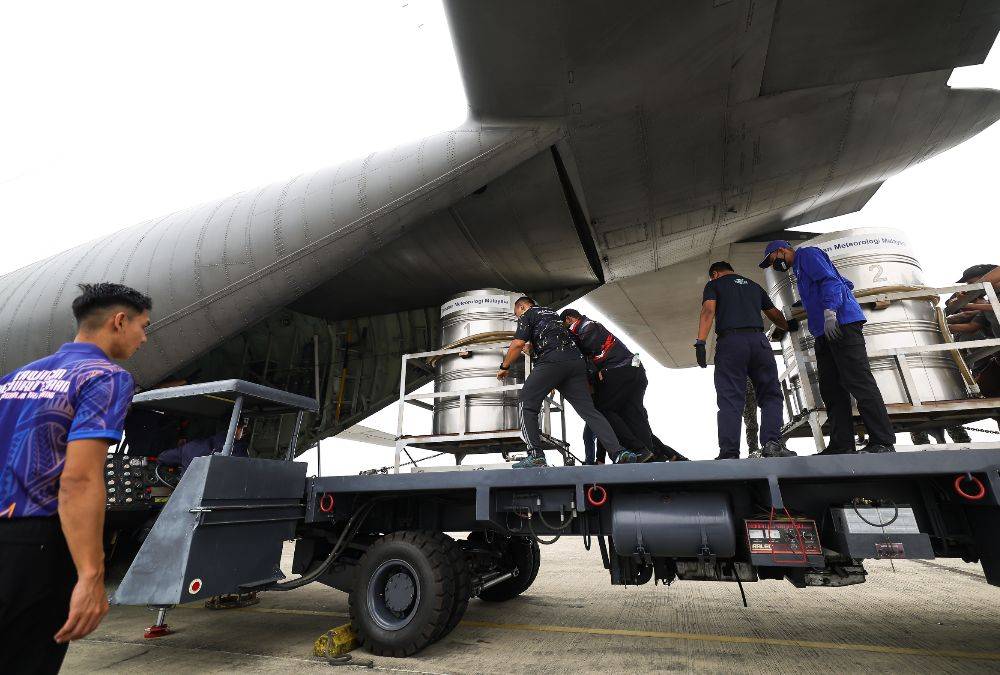 A Malaysian Meteorological Department (MET) Sarawak personnel pushes a tank containing saline solution into a Royal Malaysian Air Force (RMAF) C130 aircraft to carry out a Cloud Seeding Operation (OPA) at the RMAF Base Kuching, today. Photo by Bernama