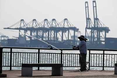 An angler fishes next to the container port terminal in Singapore on Sept 3, 2026. - (Photo by ROSLAN RAHMAN / AFP)