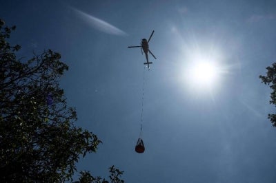 A helicopter transports relief materials in the aftermath of flash floods at Trishuli Bazar in Nepal's Nuwakot district on Sept 5. Photo by AFP