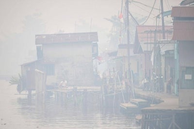 A man sits by the Kapuas river as thick smoke and haze shrouds the city of Pontianak in West Kalimantan on September 6, 2026. Indonesia has been battling for weeks to contain wildfires and thick smog, which has been drifting to Malaysia, Singapore and the Philippines. Photo by Bay Ismoyo/AFP