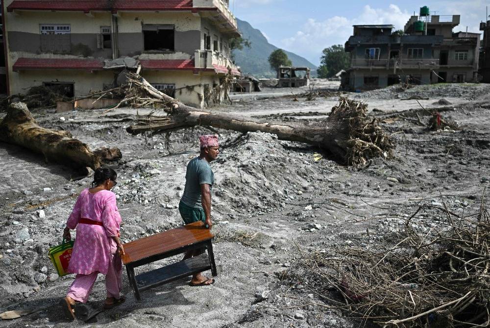 People recover their belongings in the aftermath of flash floods at Devighat in Nepal's Nuwakot district on Sept 8, 2026. The Aug 26 glacial and mountain collapse on the China-Nepal border killed at least 1,399 people, with more than 5,500 missing, including around 800 foreigners. - (Photo by PEDRO PARDO / AFP)