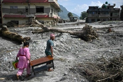 People recover their belongings in the aftermath of flash floods at Devighat in Nepal's Nuwakot district on Sept 8, 2026. The Aug 26 glacial and mountain collapse on the China-Nepal border killed at least 1,399 people, with more than 5,500 missing, including around 800 foreigners. - (Photo by PEDRO PARDO / AFP)