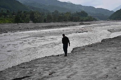 A man stands along a swollen river in the aftermath of flash floods at Devighat in Nepal's Nuwakot district on Sept 7, 2026. - (Photo by PEDRO PARDO / AFP)
