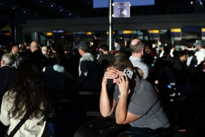 People stand with their luggage as the queue at check-in desks inside Terminal 5 of London Heathrow airport, west of London on Sept 8, 2026, following major disruption due an issue affecting the NATS air traffic control systems. - (Photo by HENRY NICHOLLS / AFP)