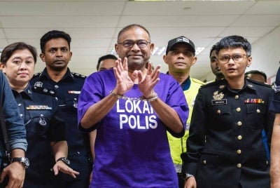 Abdul Azeez Abdul Rahim is escorted by police officers after his prosecution proceedings at the Kuala Lumpur Sessions Court on Sept 9. -Bernama Photo