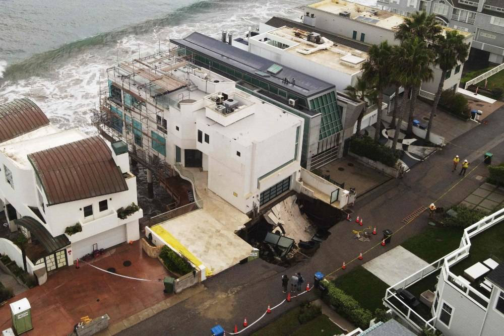 A sinkhole on a street and driveway of a seaside home affected by large swells produced by Hurricane Marie in Malibu, California. Photo by AFP