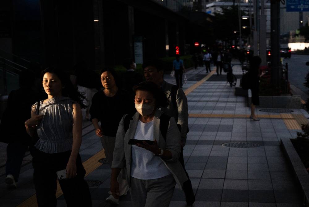 People walk down the street at the end of the work day to a metro stop in Tokyo on May 8, 2026. - (Photo by ANDREW CABALLERO-REYNOLDS / AFP)