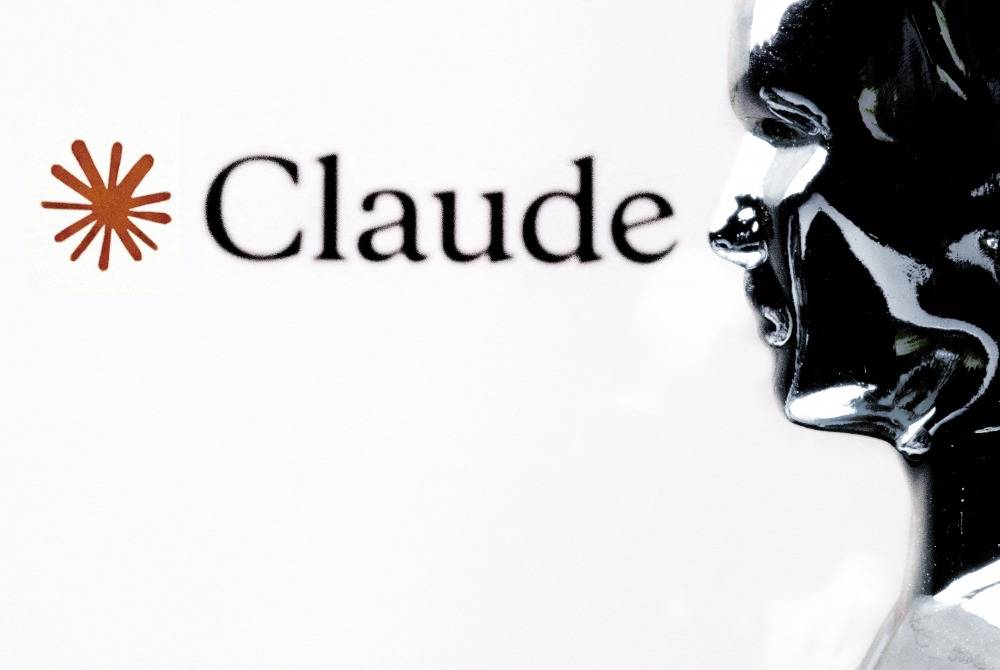 This photograph shows a figurine in front of the logo of the AI assistant "Claude" built by the US artificial intelligence safety and research company Anthropic during a photo session in Paris on Feb 13, 2026. -(Photo by JOEL SAGET / AFP)