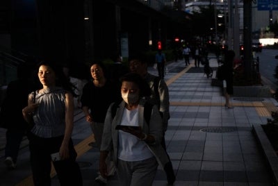 People walk down the street at the end of the work day to a metro stop in Tokyo on May 8, 2026. - (Photo by ANDREW CABALLERO-REYNOLDS / AFP)
