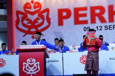 During the speech, Zahid also instructed his security personnel not to stop a supporter from coming up onto the stage, before asking him to stand in the middle holding a placard that read "Malu apa bossku". Photo by Halim Wahid