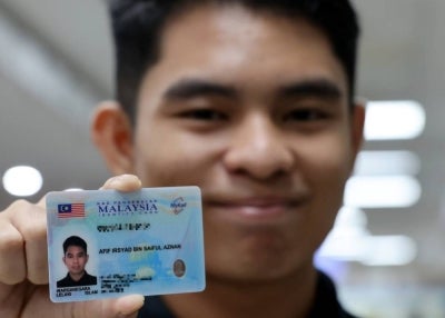 Afif Irsyad Saiful Aznan showing his new-generation MyKad at the National Registration Department (JPN), yesterday. - Photo by Bernama