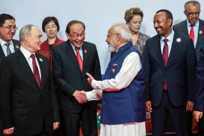 This handout photograph taken and released by Indian Press Information Bureau (PIB) on September 13, 2026 shows India's Prime Minister Narendra Modi (2R) speaking with Malaysia’s Prime Minister Anwar Ibrahim (2L) and Russia's President Vladimir Putin (L) during a gathering for a family photo at the 18th BRICS Summit in New Delhi. (Photo by Handout / AFP) 