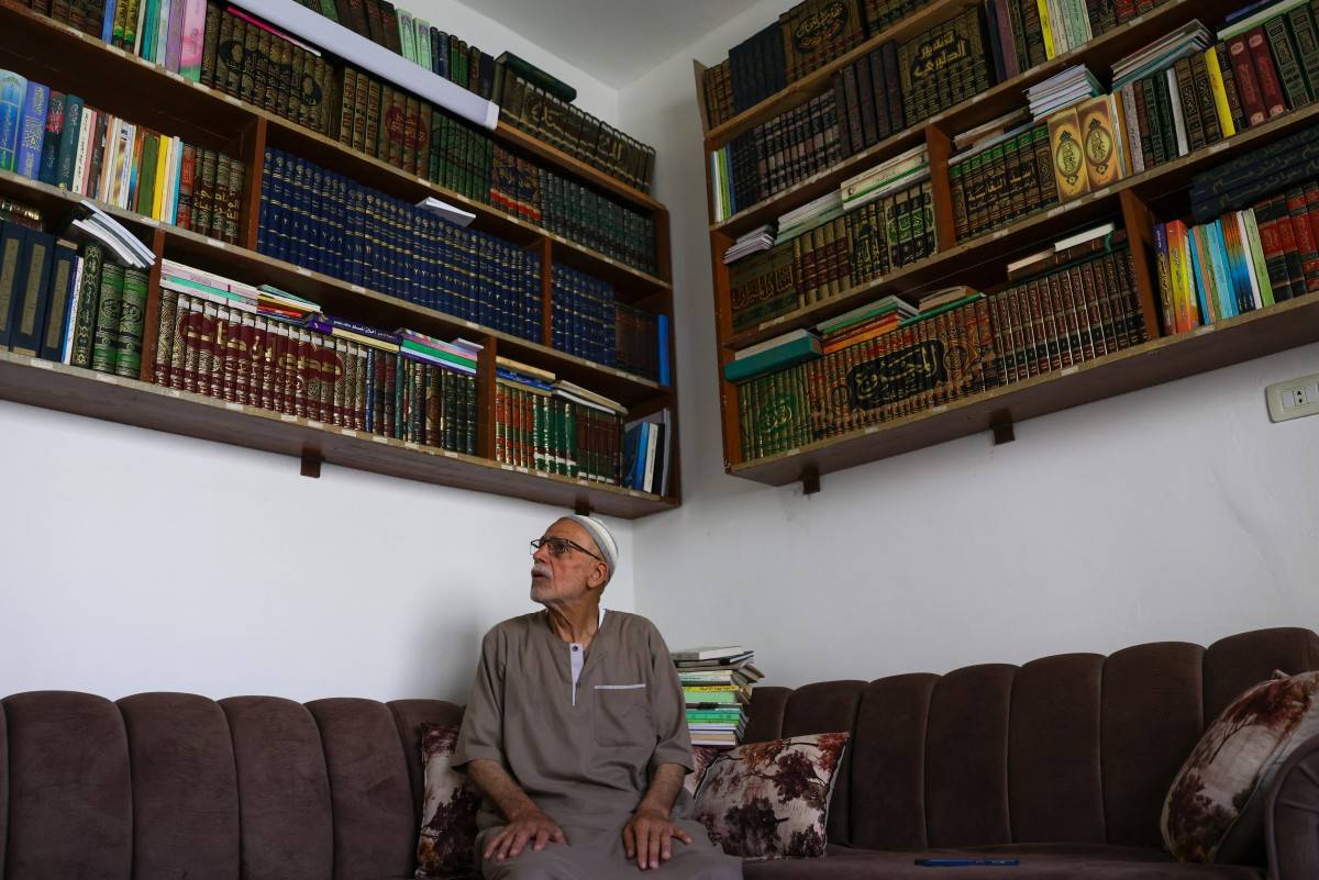 Mustafa Khaled Alwan, a 72-year-old Syrian man, poses for a picture surrounded by his books, which he retrieved after hiding them behind a false wall for 15 years at the start of the uprising against longtime Syrian ruler Bashar al-Assad, in his home in the al-Bayadah neighbourhood in Homs on September 19, 2026. (Photo by Bakr ALKASEM / AFP)