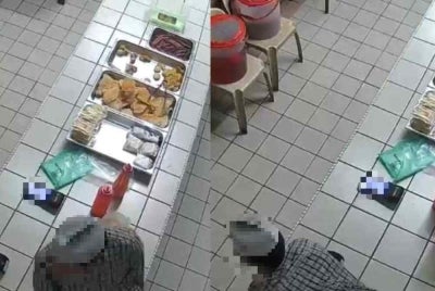 A screen grab of CCTV footage showing the student climbing over the counter and taking money kept beside the cash box.