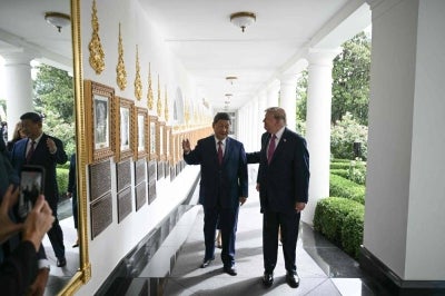 US President Donald Trump and China's President Xi Jinping walk in the Colonnade before holding a bilateral meeting in the Oval Office of the White House in Washington, DC. Photo by AFP