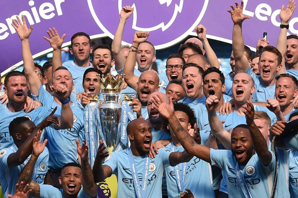 Manchester City's Spanish manager Pep Guardiola (C) holds the Premier League trophy on the pitch with Manchester City players after the English Premier League football match between Manchester City and Huddersfield Town at the Etihad Stadium in Manchester, north west England, on May 6, 2018. (Photo by OLI SCARFF / AFP)