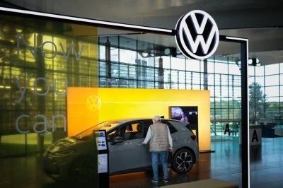 A visitor stands by a ID.Polo car in the customer centre at the headquarters of German carmaker Volkswagen (VW) in Wolfsburg, Germany. German car giant Volkswagen had announced earlier in September 2026 that management and unions had agreed to cut a total of 100,000 jobs by the end of the decade, the biggest-ever restructuring in the global auto industry. (Photo by Ronny HARTMANN / AFP)